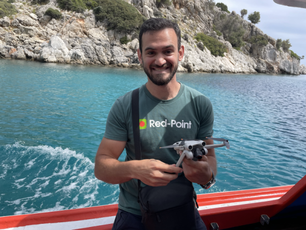 Um homem usando uma camiseta do Red-Point segurando um drone em ambiente externo.